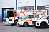 Tre elektriske kjøretøy fra Presis vegdrift står utenfor et industribygg.